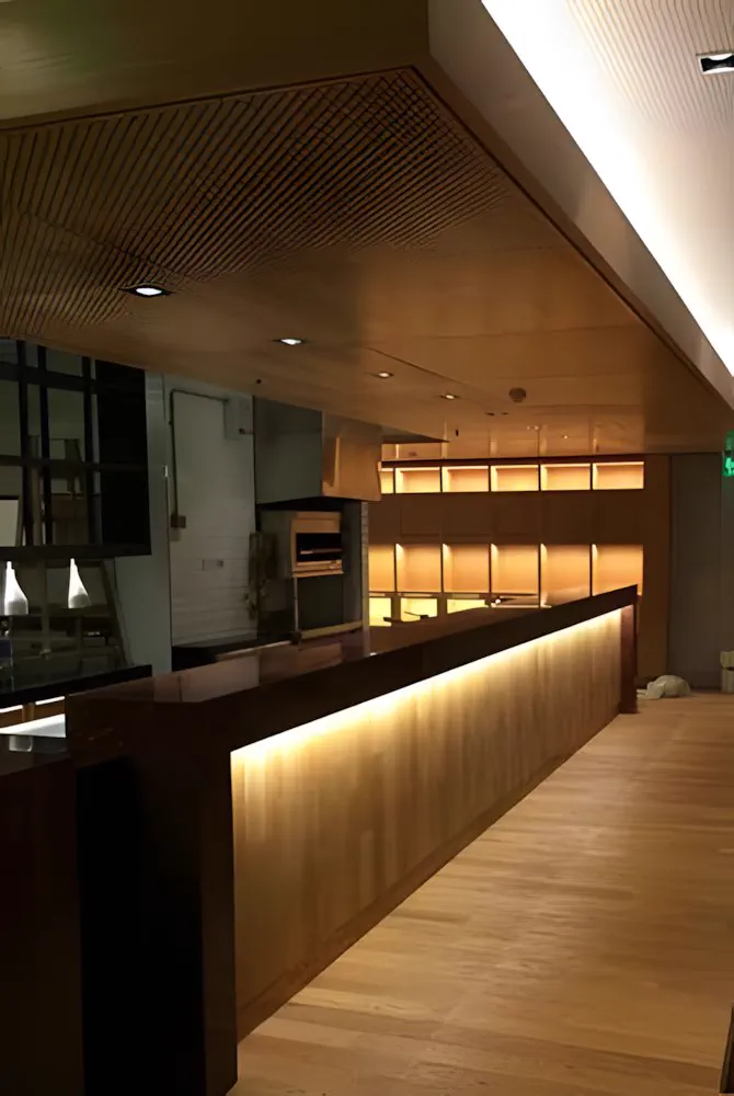 Barra larga de madera con luz rasante bajo el mostrador
