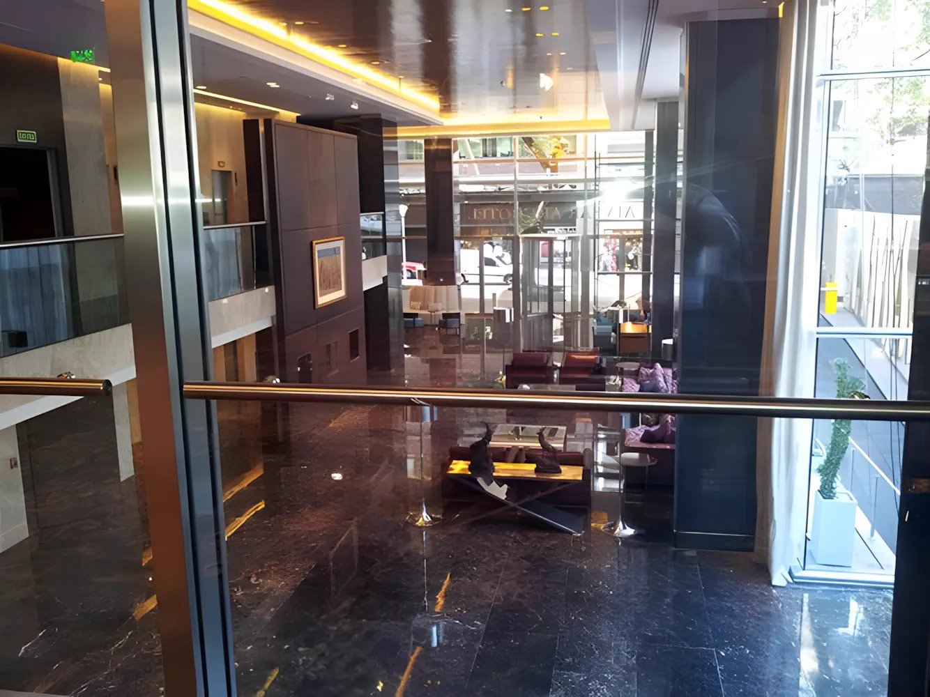 Lobby del hotel visto a través del vidrio, con la vereda al fondo