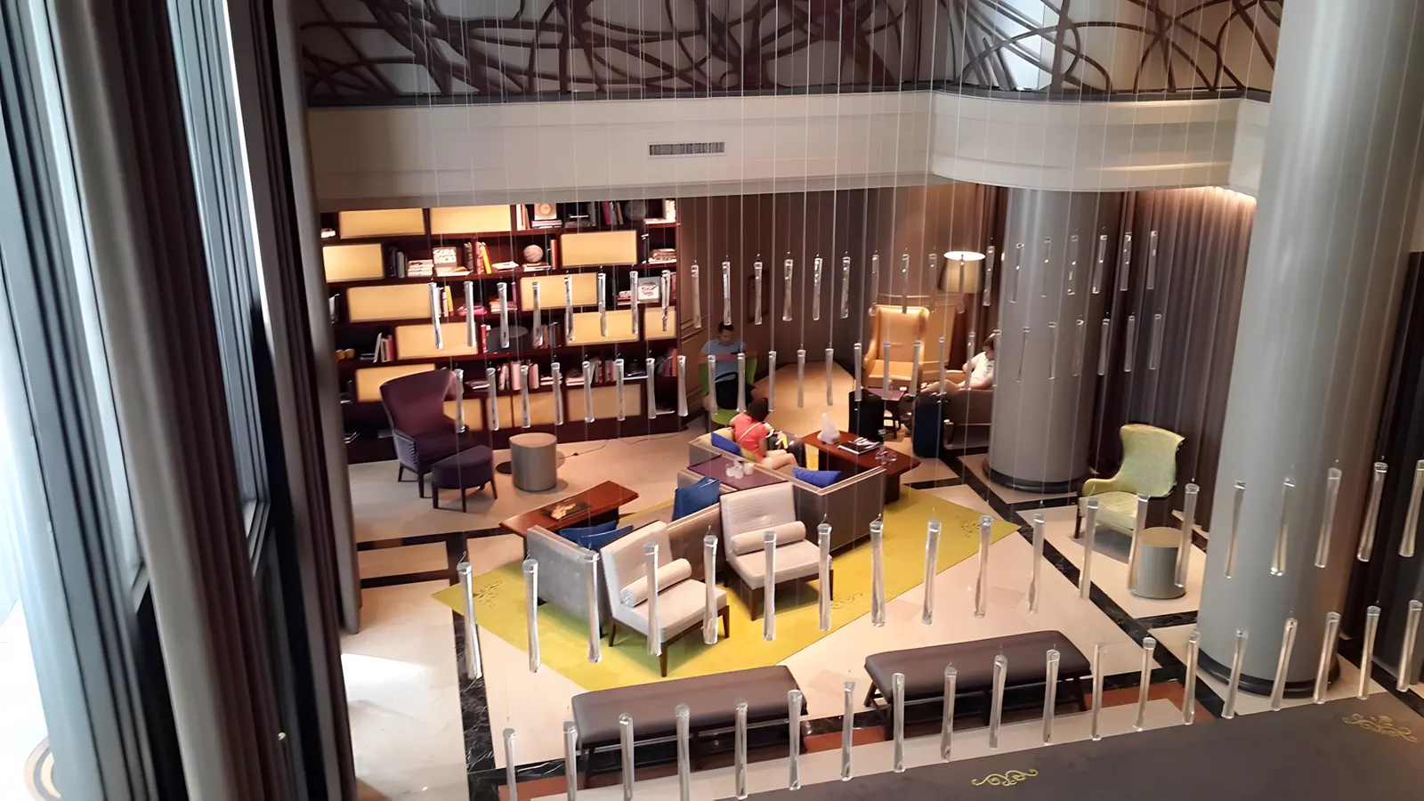 Biblioteca del hotel en doble altura, con los sillones y las estanterías