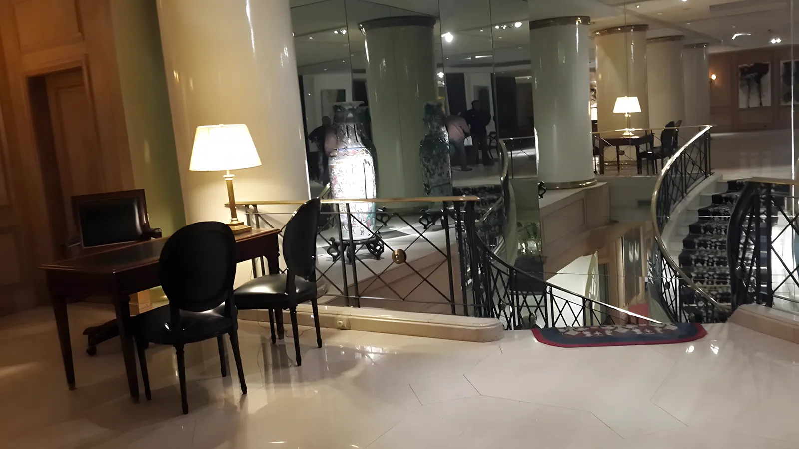 Rincón de estar junto a la escalera, con la lámpara de pie encendida