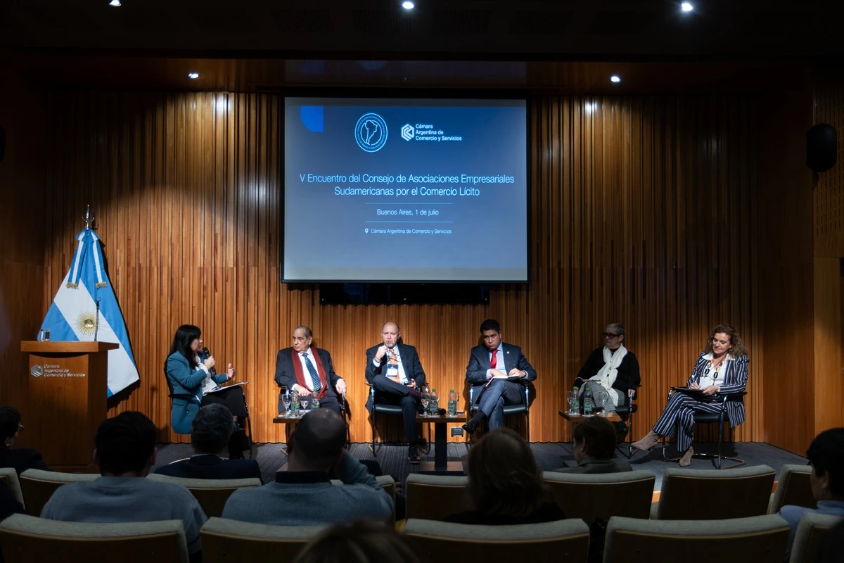 Auditorio de la Cámara Argentina de Comercio y Servicios durante un panel, con la pantalla al fondo y la luz sobre el revestimiento de madera