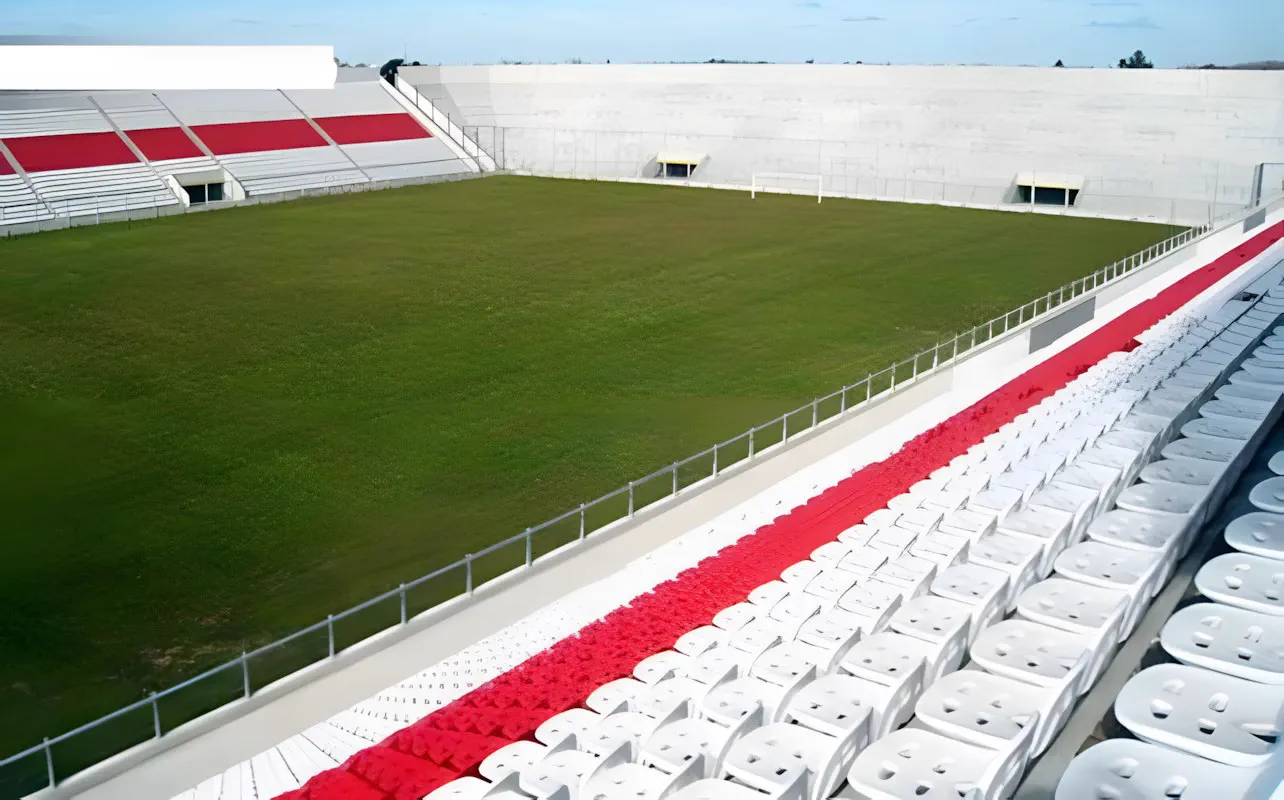 La cancha desde el borde, con la tribuna roja y blanca al fondo