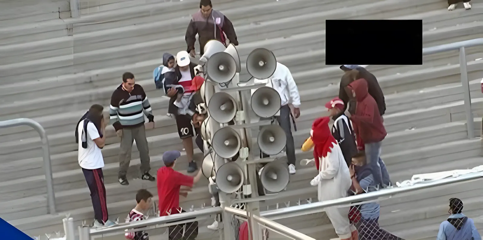 Hinchas en la tribuna, con el mástil de bocinas al costado