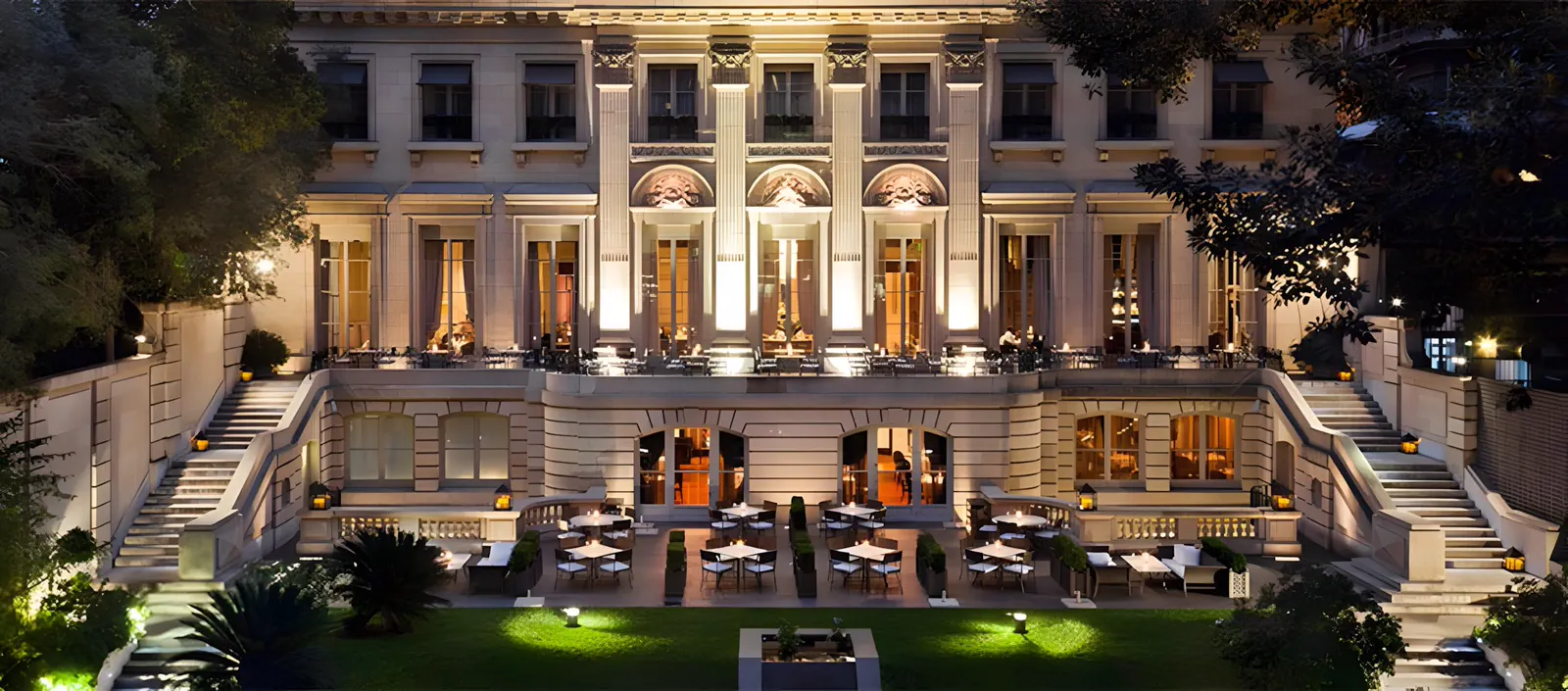Fachada del Palacio Duhau iluminada de noche, desde el jardín