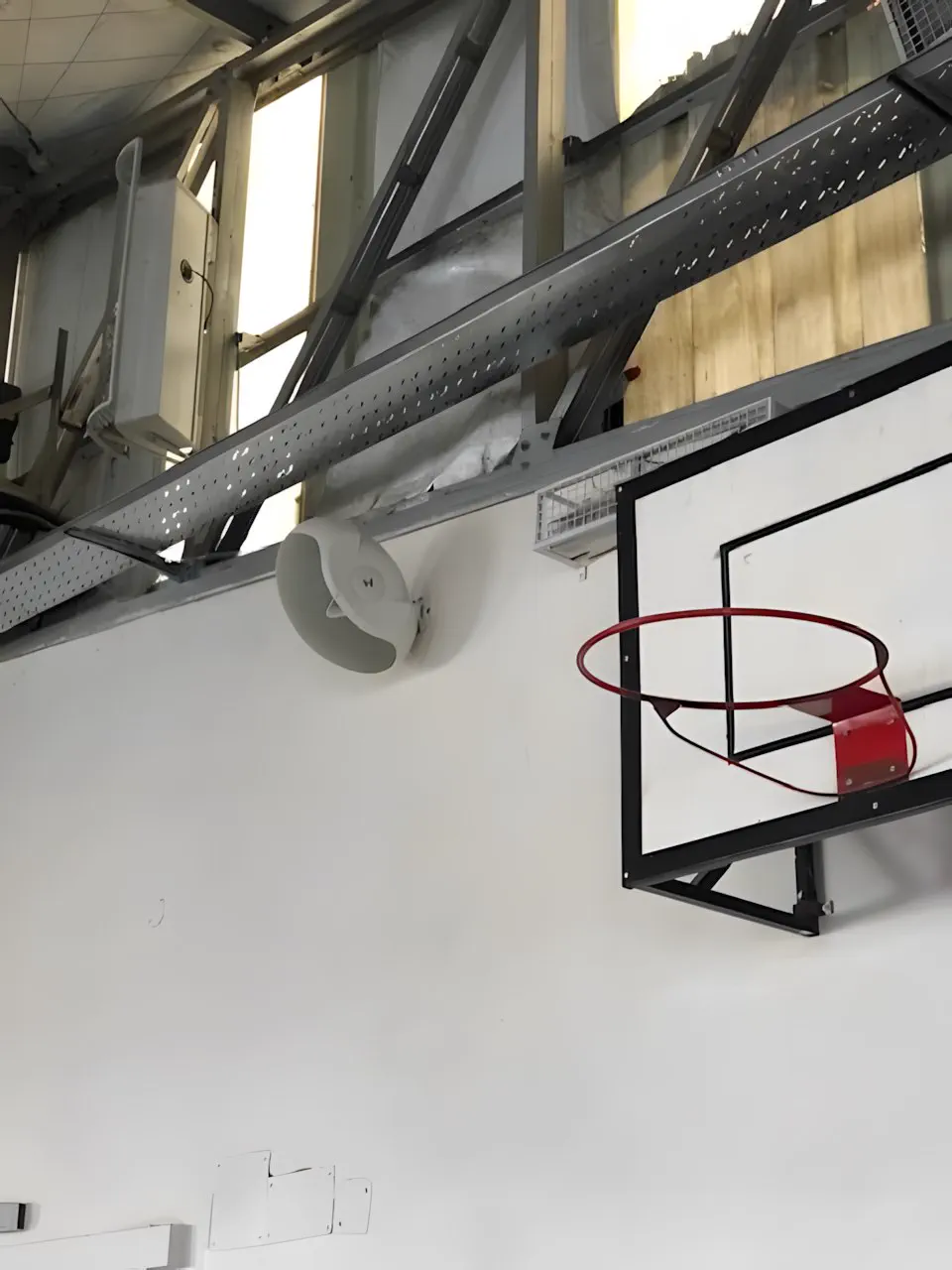 Parlante y aro de básquet en el gimnasio, bajo el techo de chapa