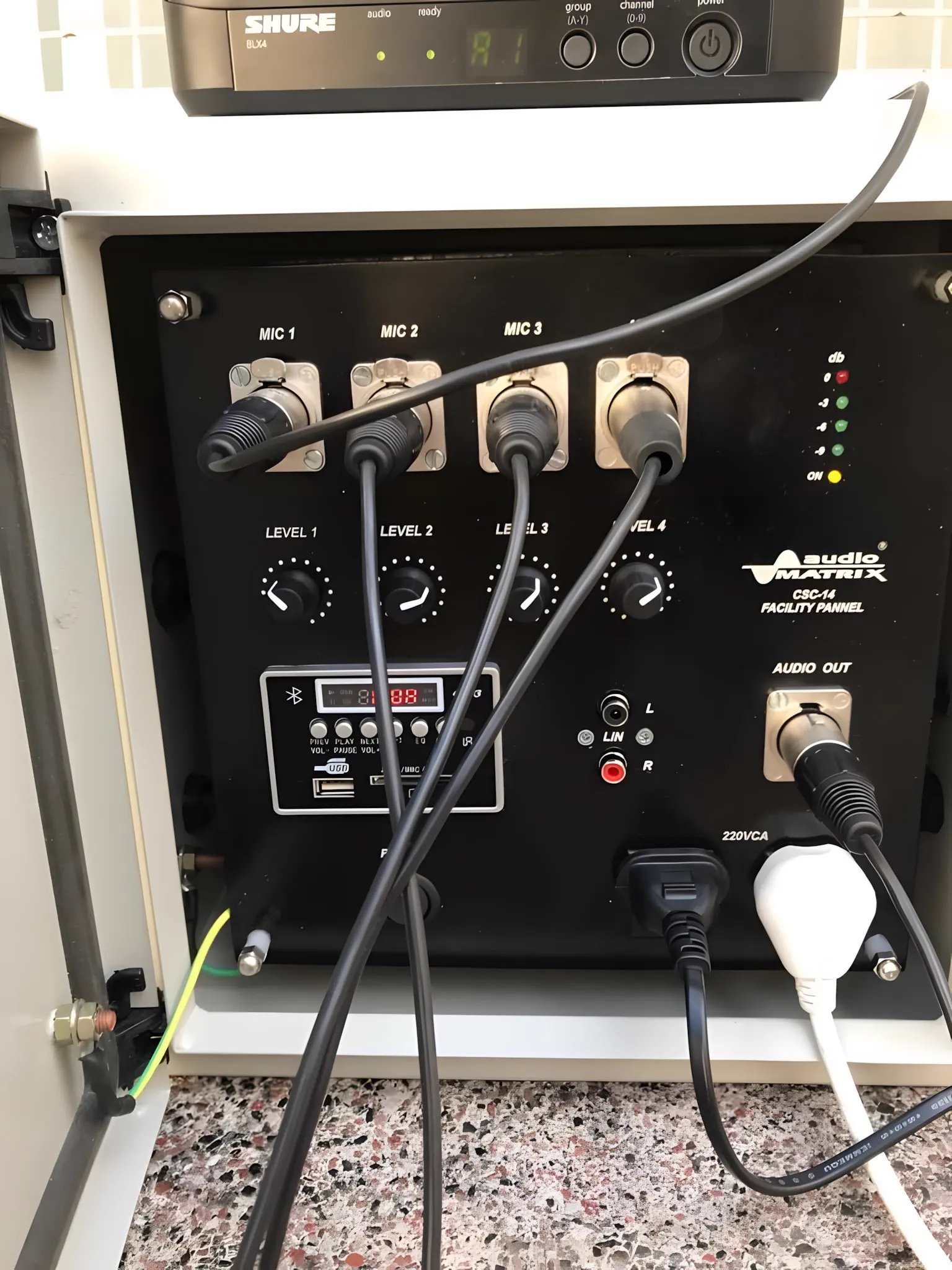 Gabinete de audio abierto a la intemperie, con los cables de micrófono conectados al frente
