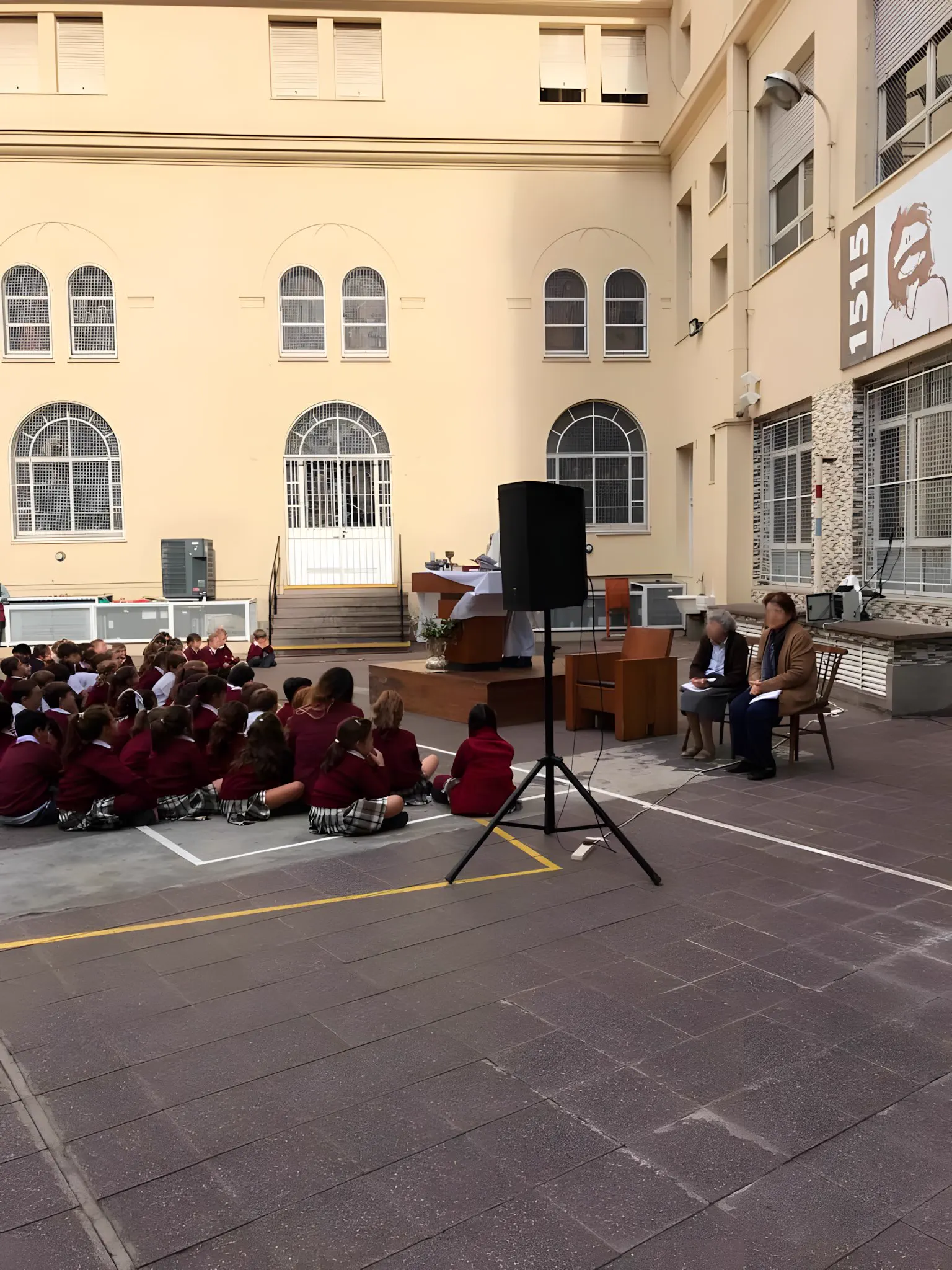 Acto en el patio, con un parlante sobre trípode a un costado del escenario