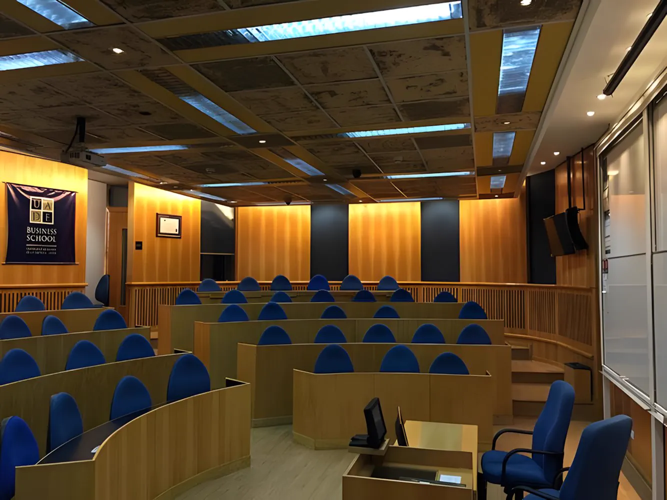 Aula en anfiteatro de UADE con las butacas azules y los pupitres de madera