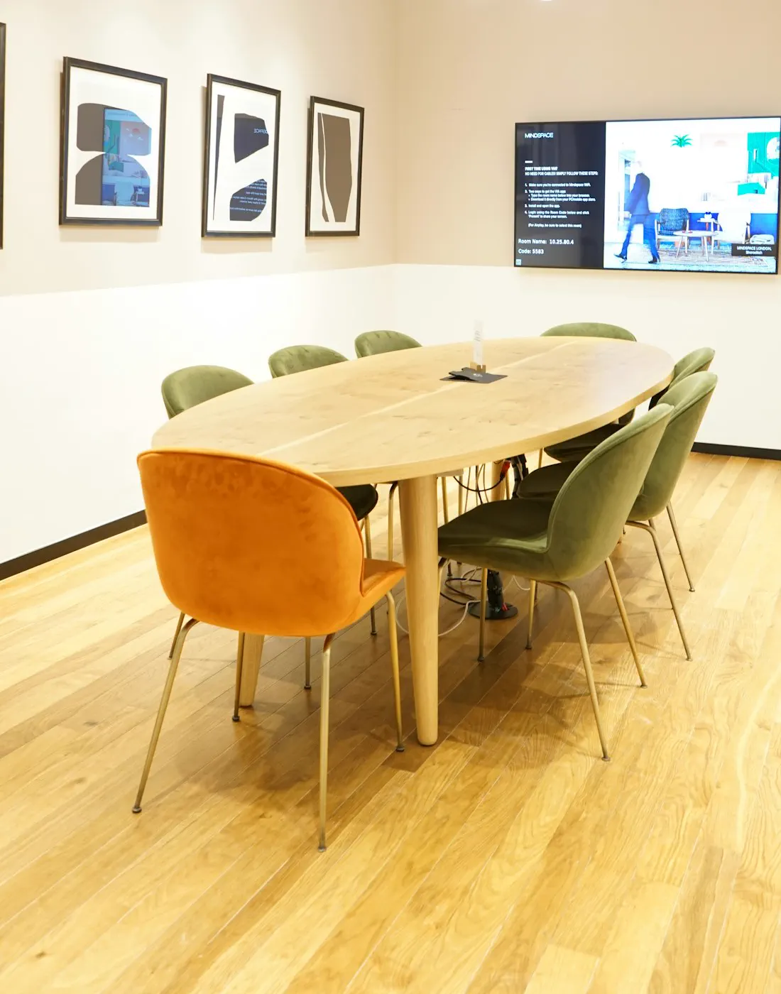 Sala de reuniones con pantalla de videoconferencia y mesa larga