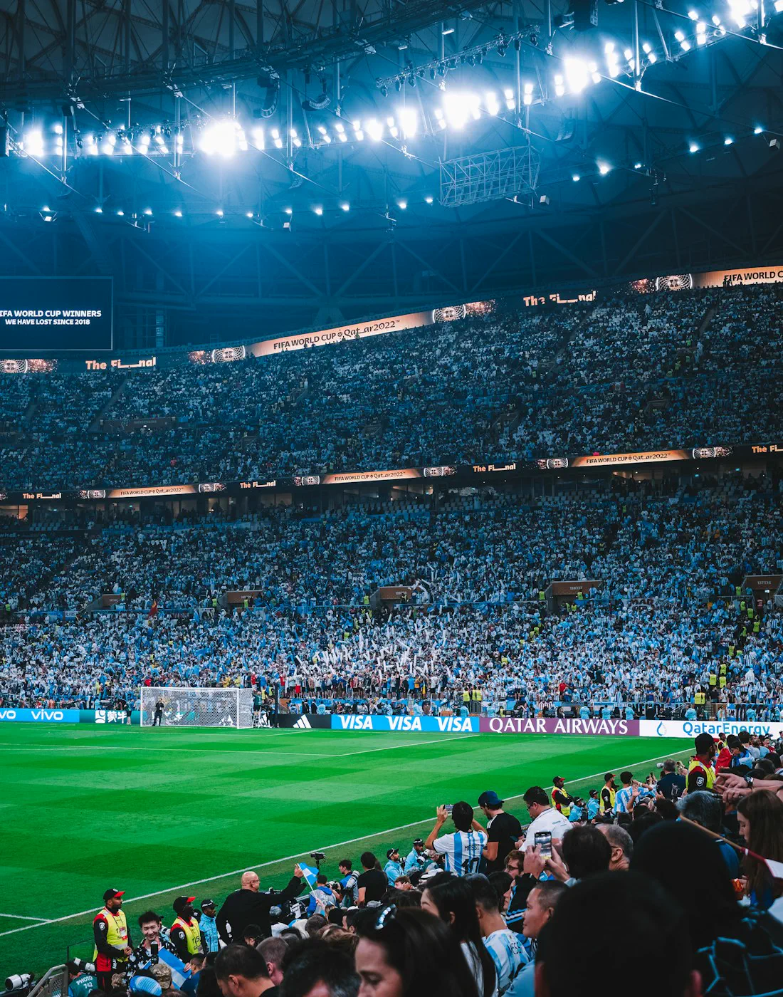 Estadio de fútbol lleno de noche, con la tribuna iluminada