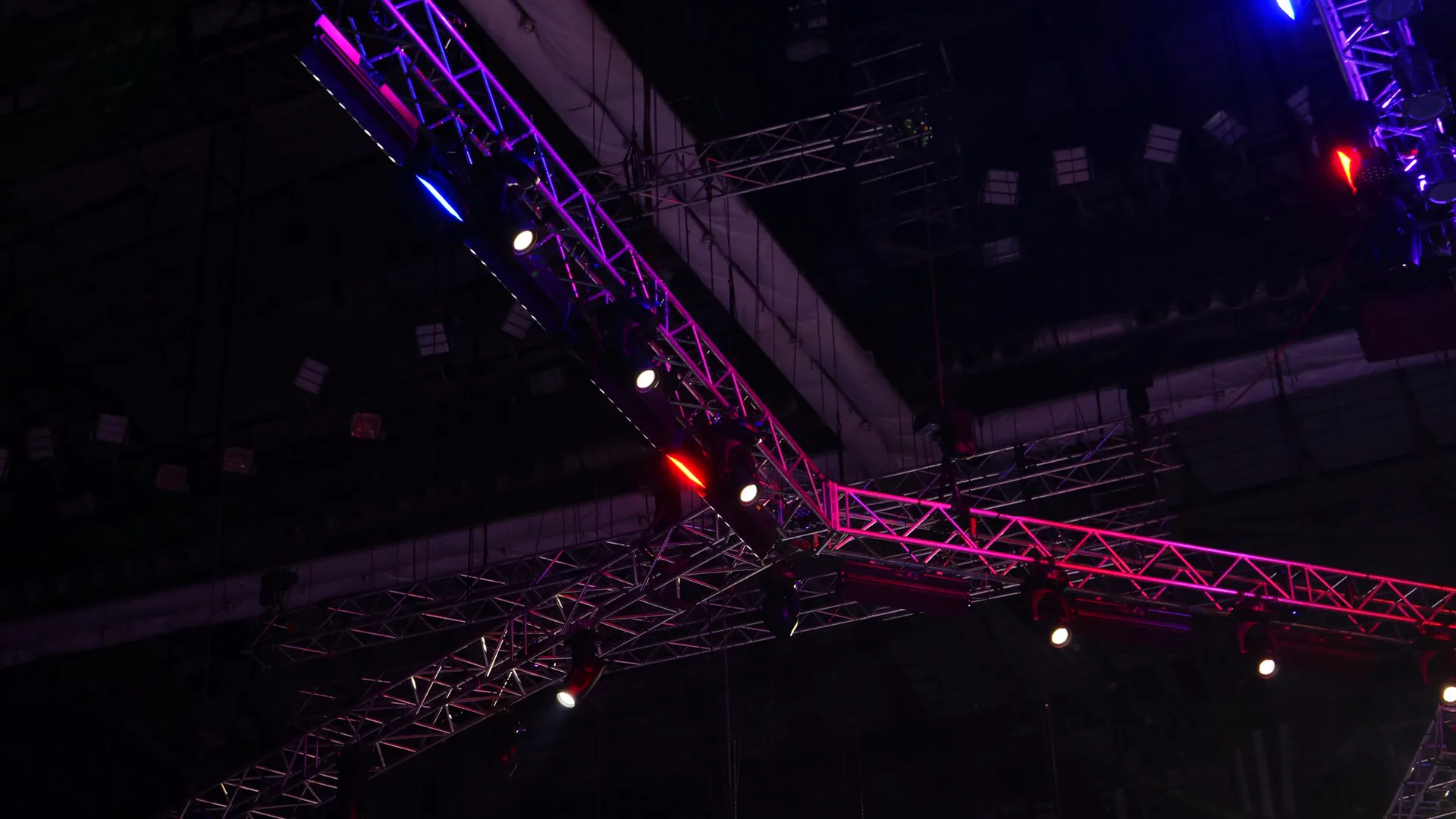 Estructuras de truss con luminarias móviles encendidas en magenta y azul