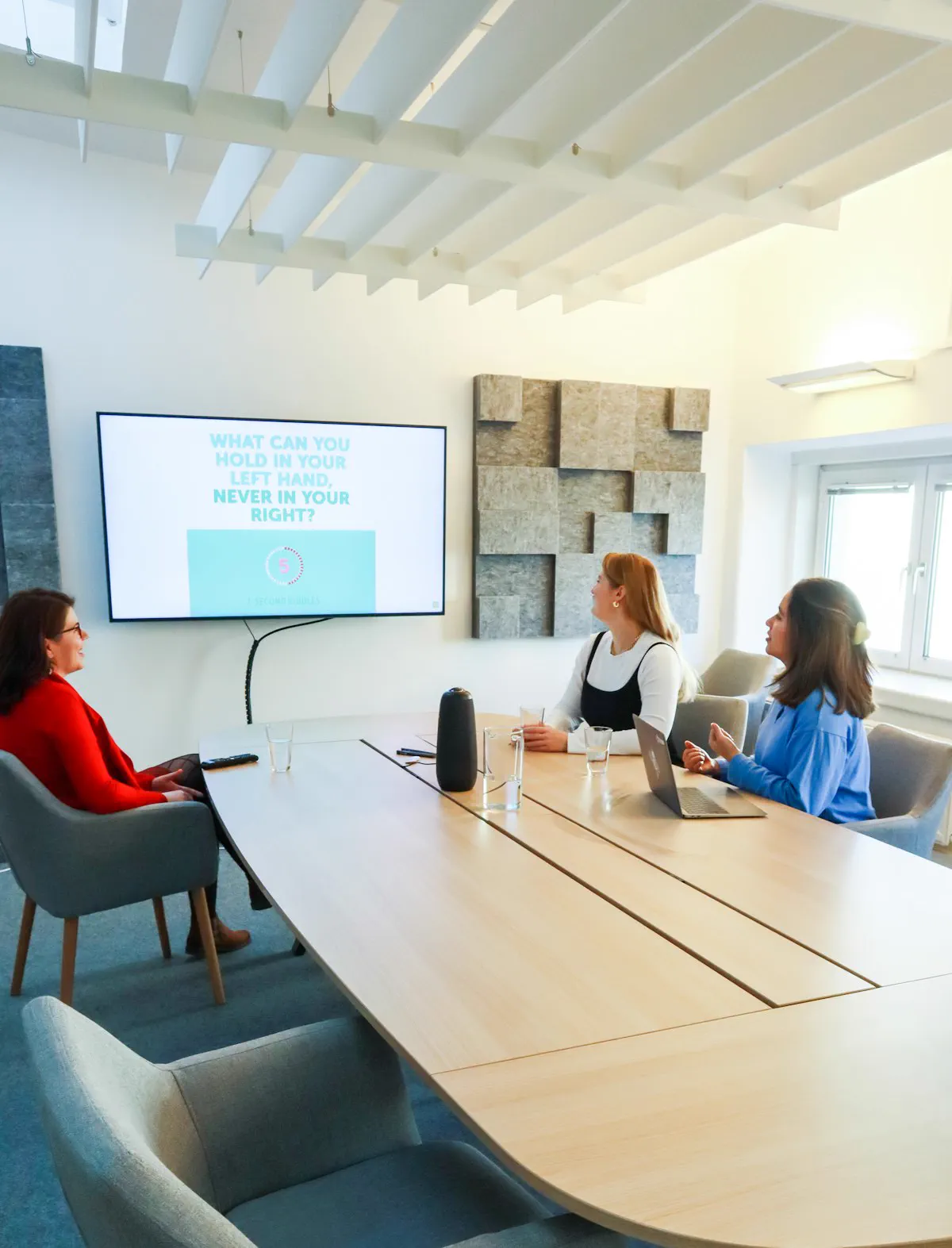 Sala de reuniones con pantalla en la pared y la mesa ocupada